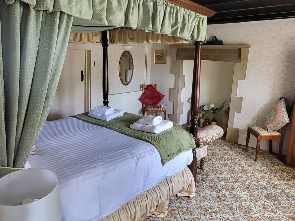 A bedroom with a four-poster bed and a chair at The Farmhouse in Youlgreave