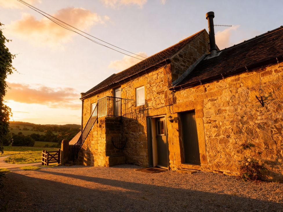An outdoor view of a stone building with a staircase at The Dairy in Middleton near Youlgreave