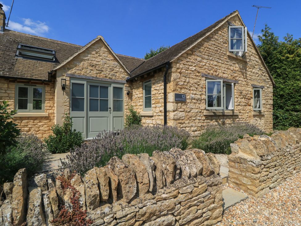 The exterior of a house with a stone wall and garden at 12 Manor Farm Close Kingham