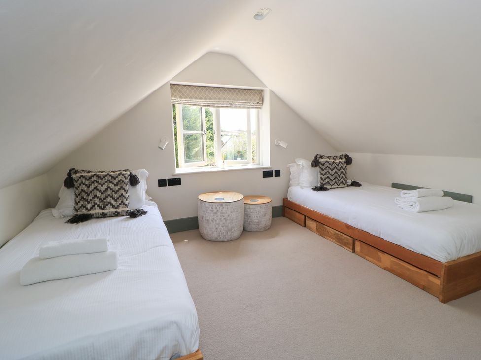 A bedroom with two beds and a window at 12 Manor Farm Close Kingham