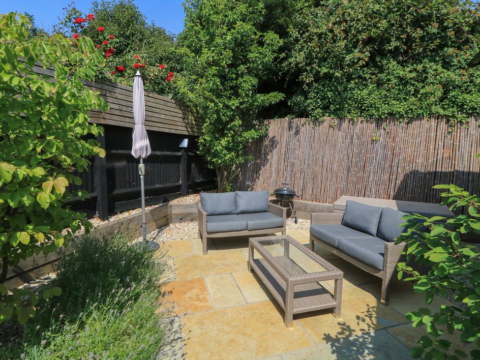 A garden with outdoor seating and a coffee table at 12 Manor Farm Close in Kingham