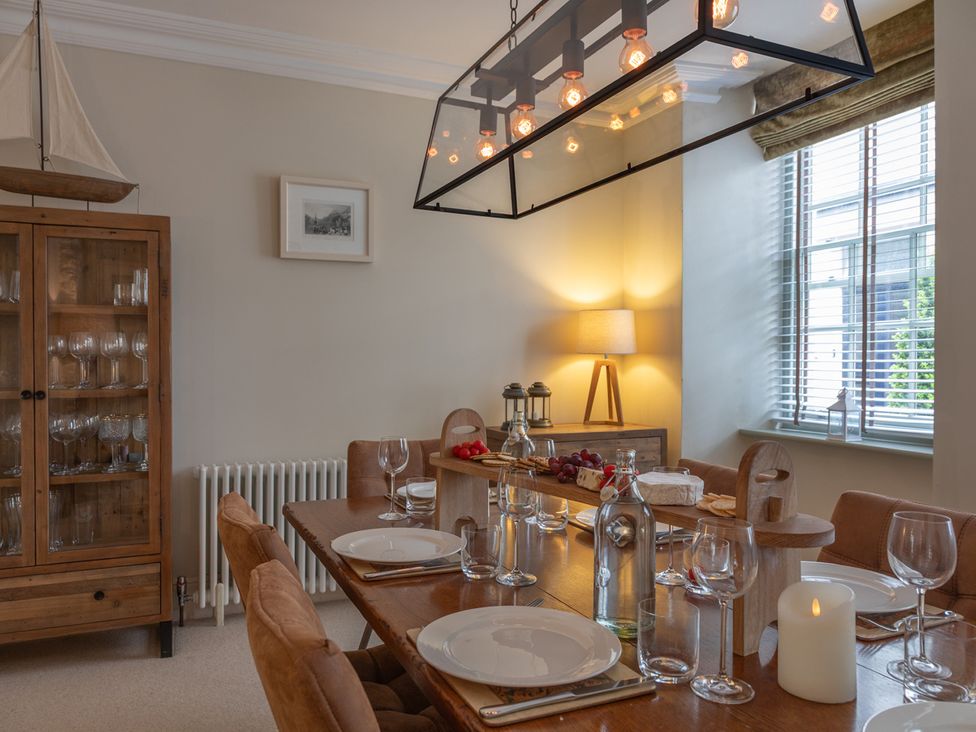 A dining room with a wooden table and glasses at George House in Dartmouth