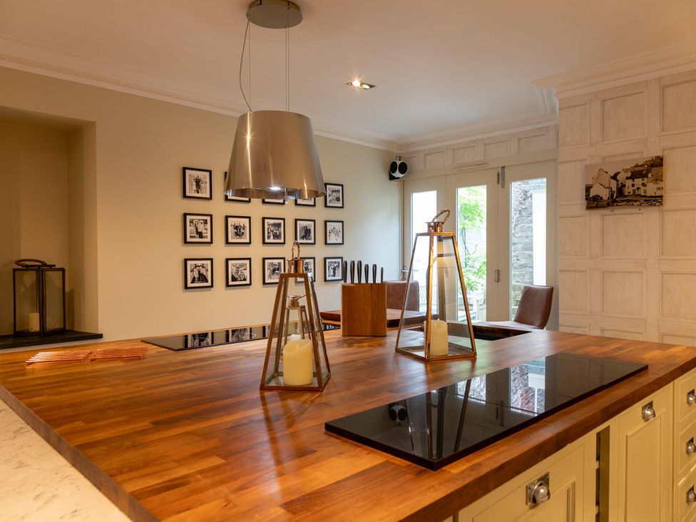 A kitchen with a wooden island and framed photos at George House Dartmouth