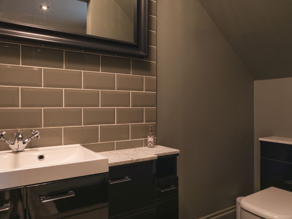 A bathroom with a sink, toilet, and mirror at George House in Dartmouth