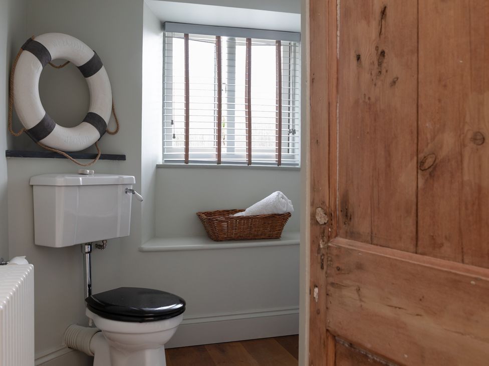 A bathroom featuring a toilet and a basket with towels at George House in Dartmouth