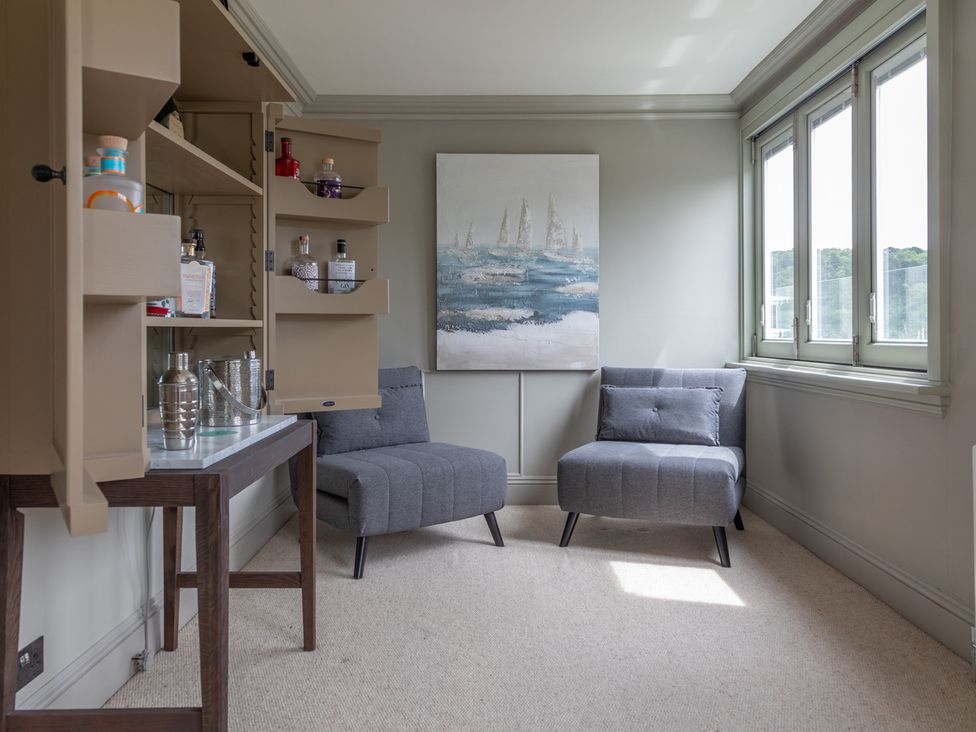 A snug with two armchairs and a shelving unit at George House in Dartmouth