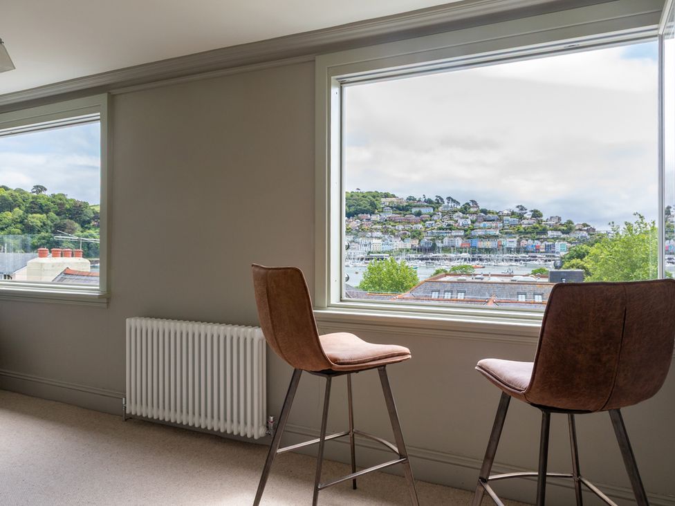 A room with bar stools and windows looking at a waterfront at George House in Dartmouth