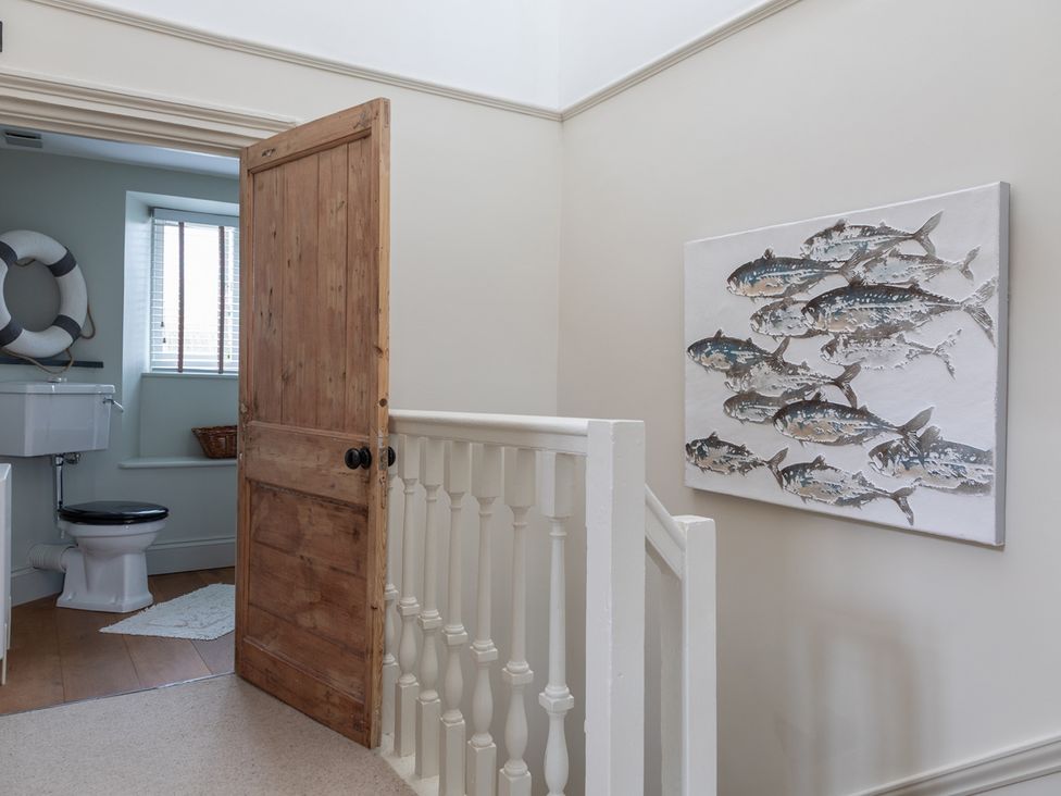 A bathroom with a toilet and a fish painting at George House in Dartmouth