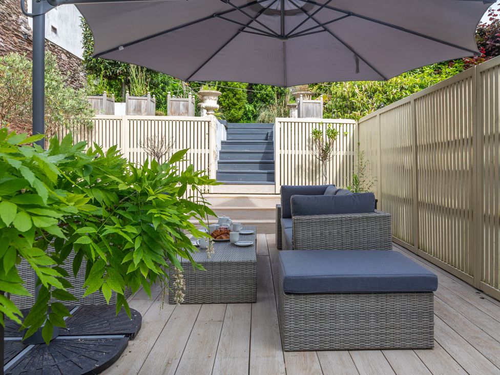 A garden with furniture under an umbrella at George House in Dartmouth