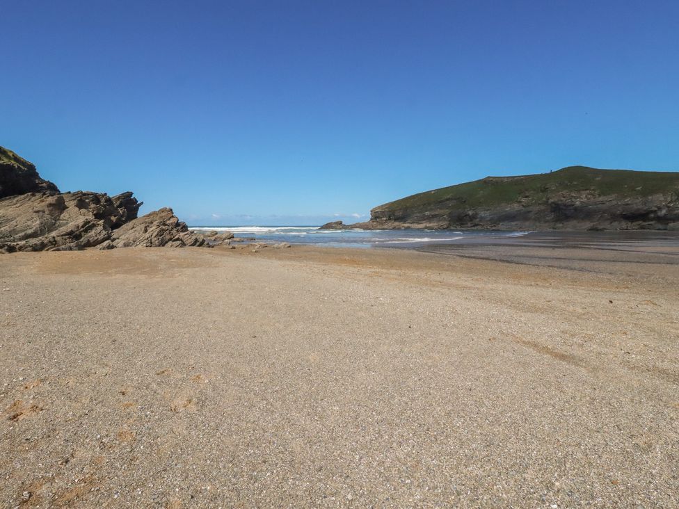 A beach with sand and rocks at Porth Cove in Porth