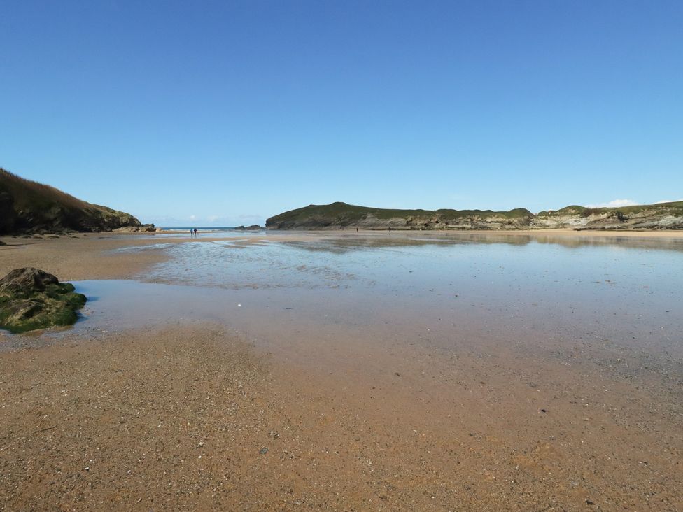 A beach with water and hills at Porth Cove in Porth