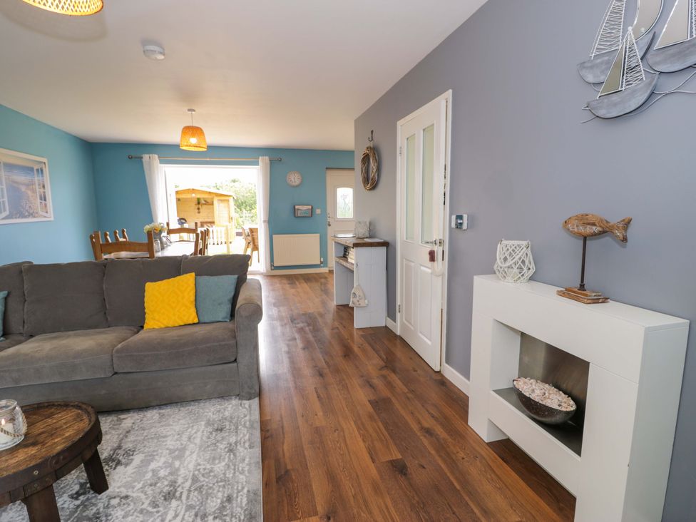 A living room with a sofa and dining area at Cae Berllan in Mynytho near Pwllheli