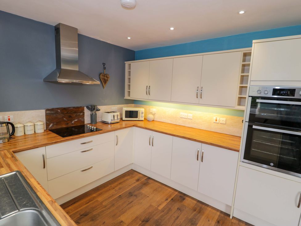 A kitchen with cabinets, countertop, stove, kettle, toaster, and microwave at Cae Berllan in Mynytho near Pwllheli