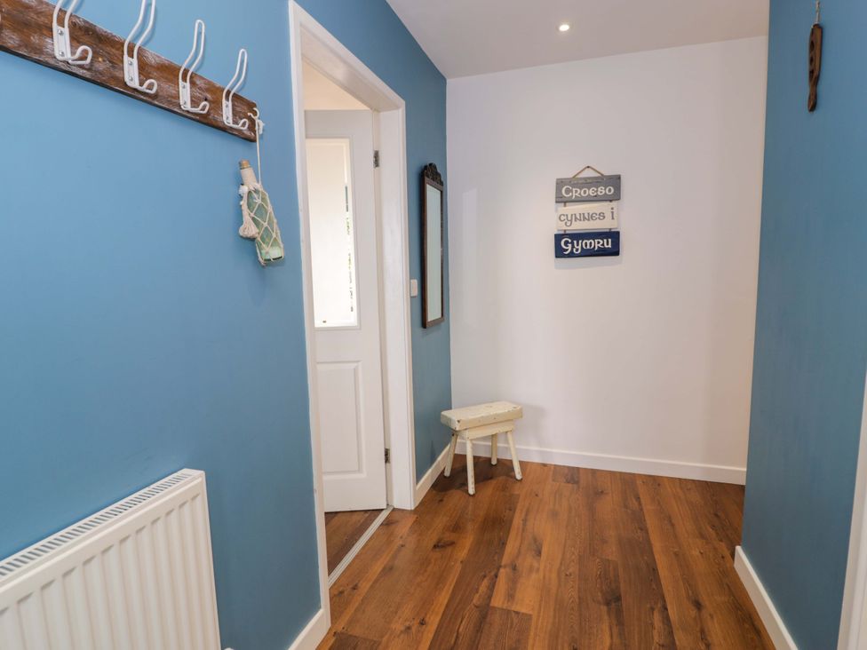 A hallway with coat hooks and a mirror at Cae Berllan in Mynytho near Pwllheli