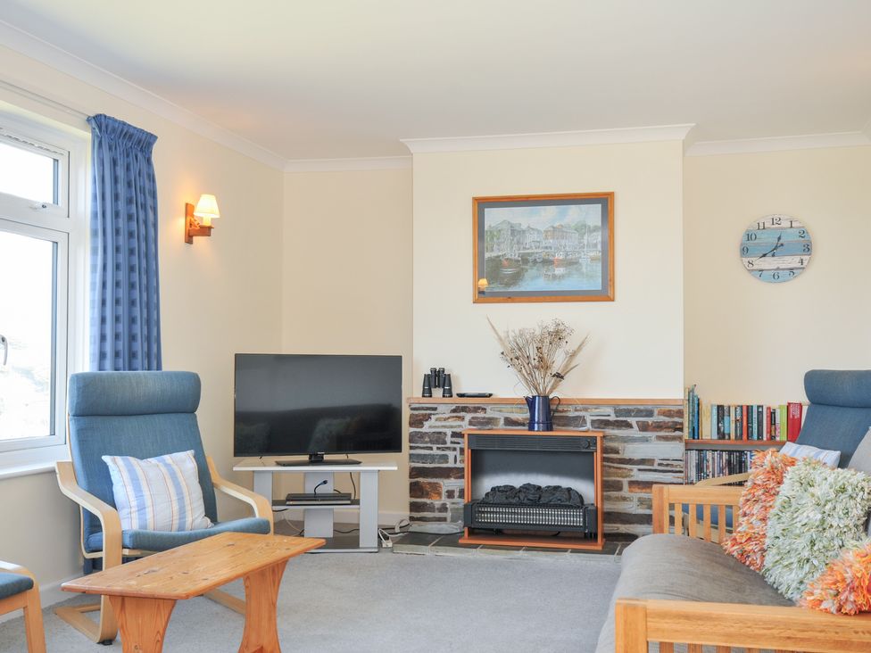A living room with a television and bookshelf at Zapadiah in Polzeath