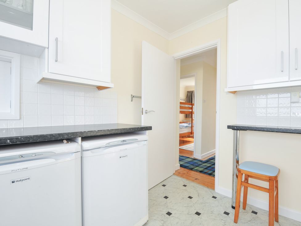 A kitchen with a dishwasher and a door leading to another room at Zapadiah in Polzeath