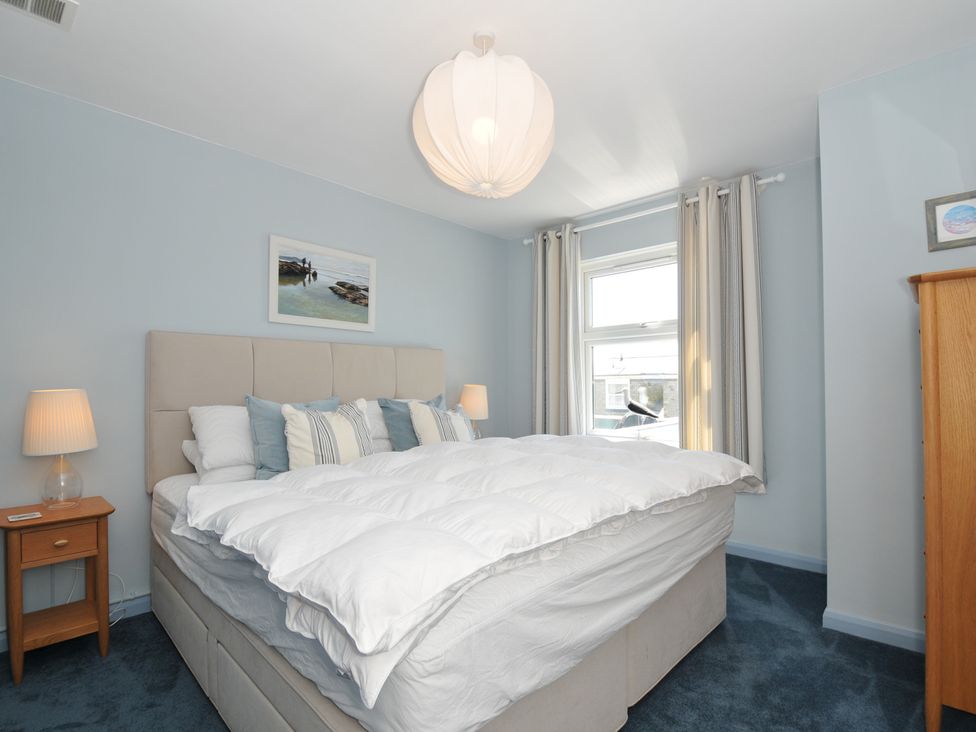 A bedroom with a bed with pillows and bedside tables with lamps at Slipway 16 in Rock