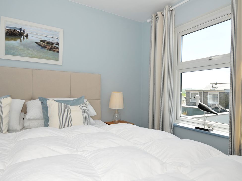 A bedroom with a bed pillows a bedside table lamp a window with curtains and a bird decoration at Slipway 16 in Rock