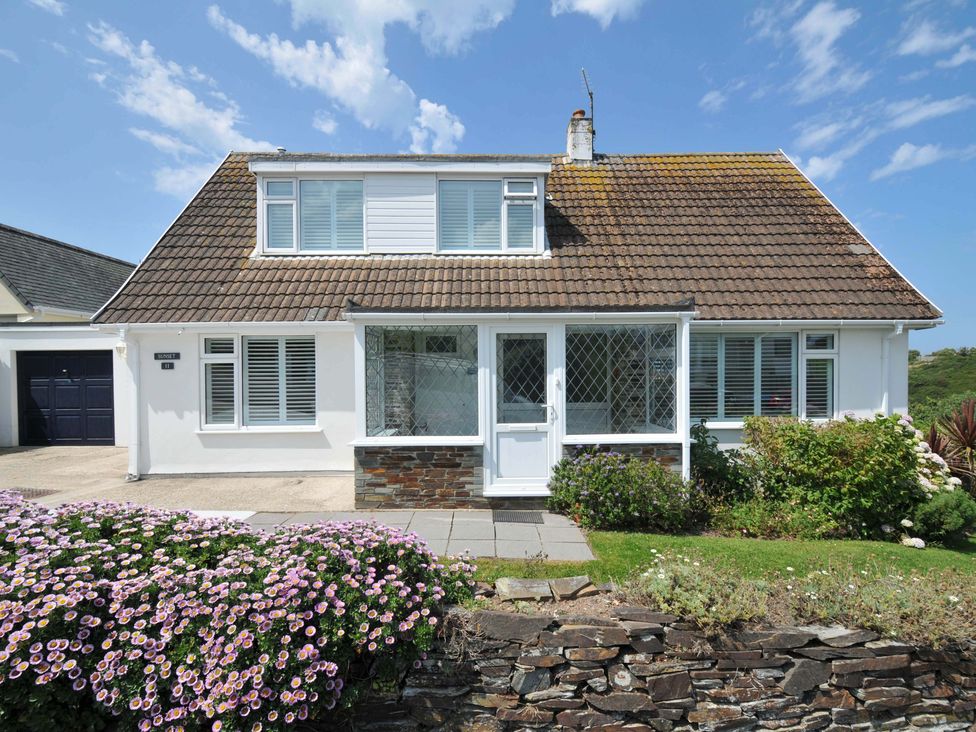 A house with a flower bed and garage at Sunset in Polzeath