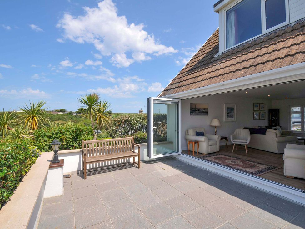 An outdoor terrace with bench and sliding door at Sunset in Polzeath