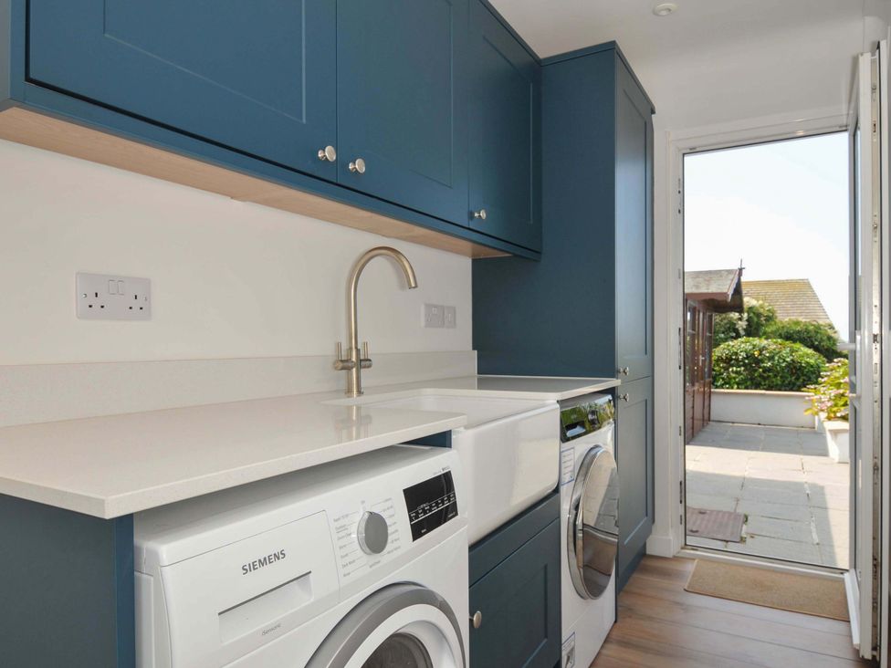 A laundry room with a washing machine and sink at Sunset in Polzeath