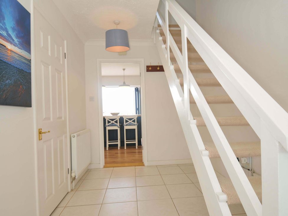A hallway with a staircase and painting at Sunset in Polzeath