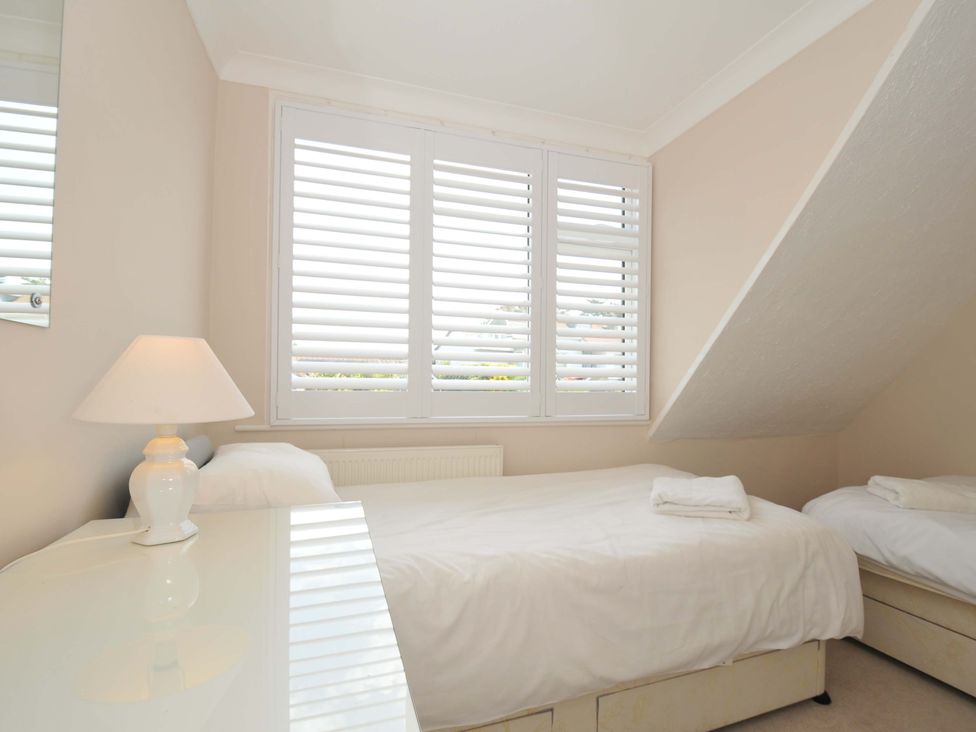 A bedroom with two single beds and a window at Sunset in Polzeath