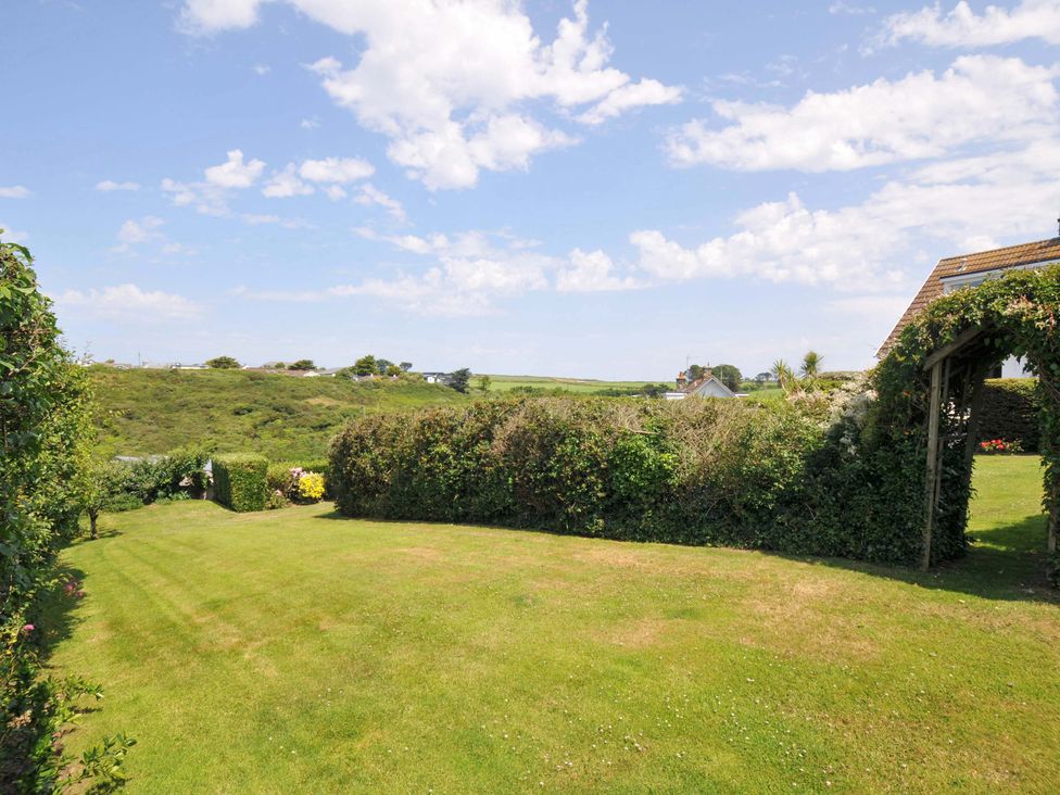 A garden with grass and hedge at Sunset in Polzeath