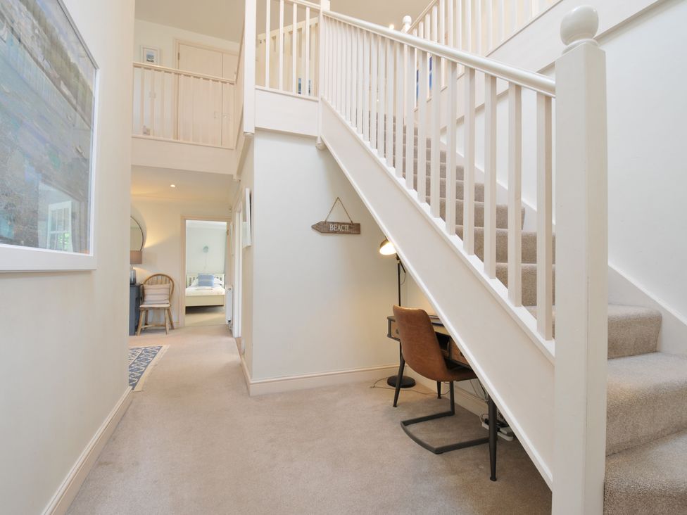 A hallway with a staircase and desk at Farlands in Daymer Bay