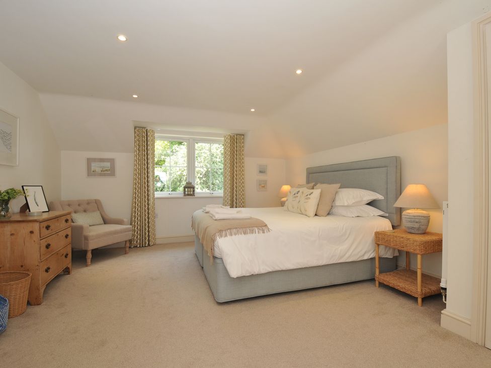 A bedroom with a bed and a chair at Farlands in Daymer Bay