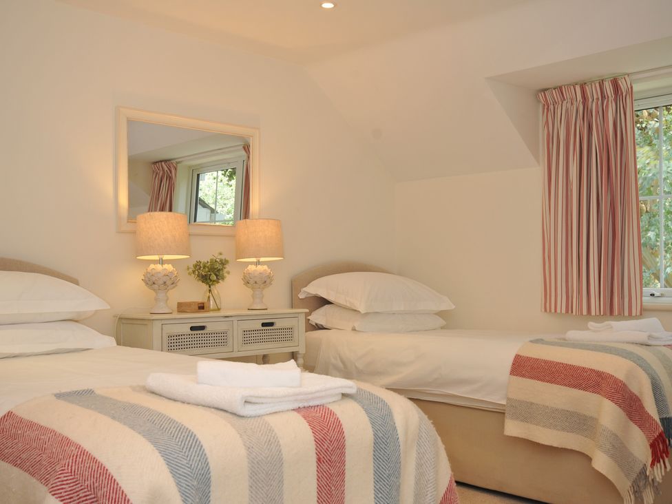 A bedroom with two beds and a mirror at Farlands in Daymer Bay