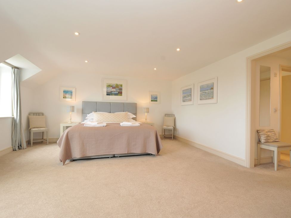 A bedroom with a bed, bedside tables, and artwork at Farlands, Daymer Bay