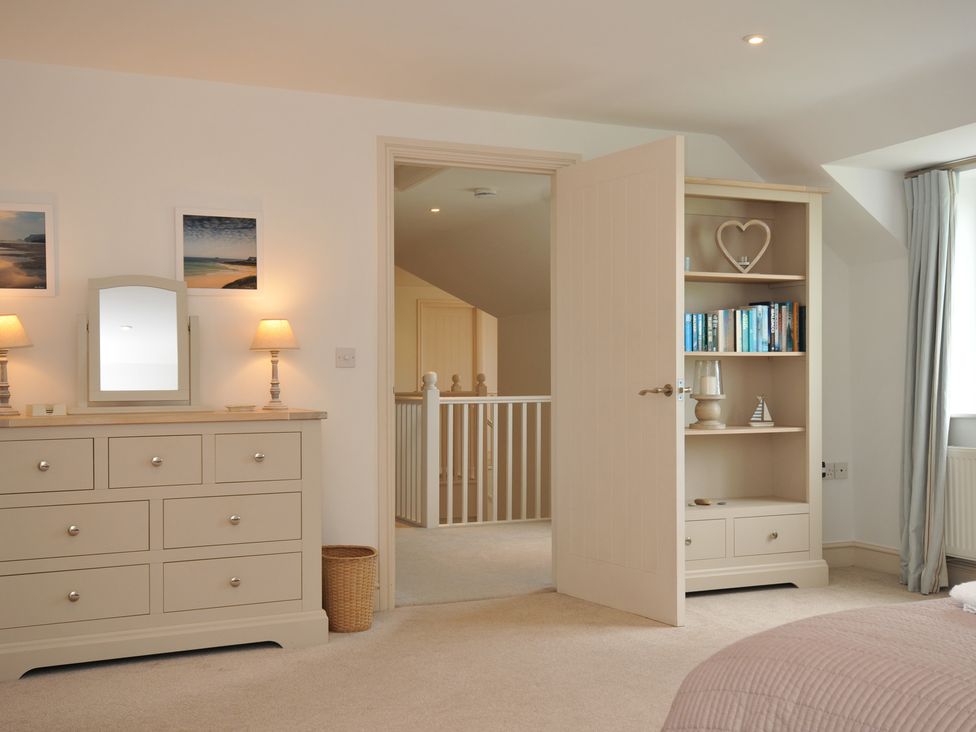 A bedroom with a dresser and open bookshelf at Farlands in Daymer Bay
