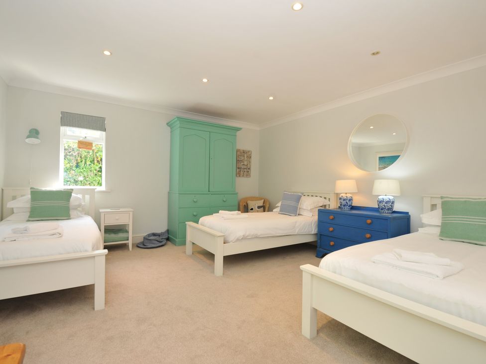 A bedroom with three beds and a blue dresser at Farlands in Daymer Bay