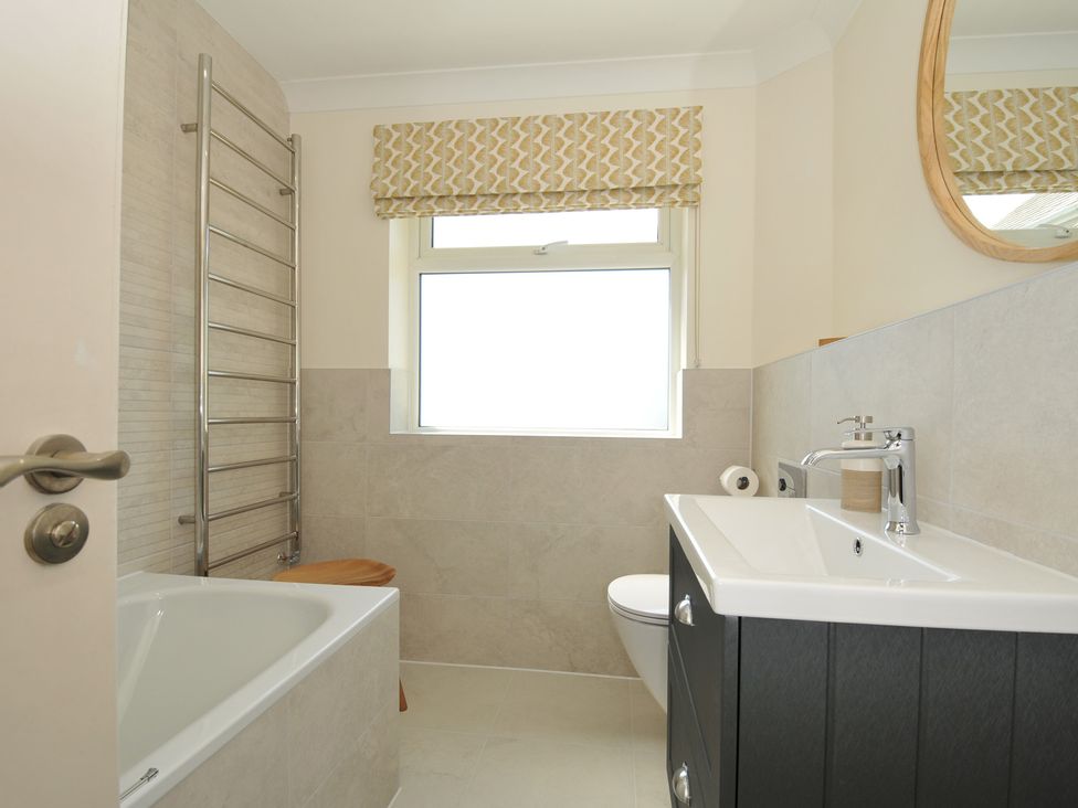 A bathroom featuring a tub, toilet, sink, and towel rail at Farlands Daymer Bay