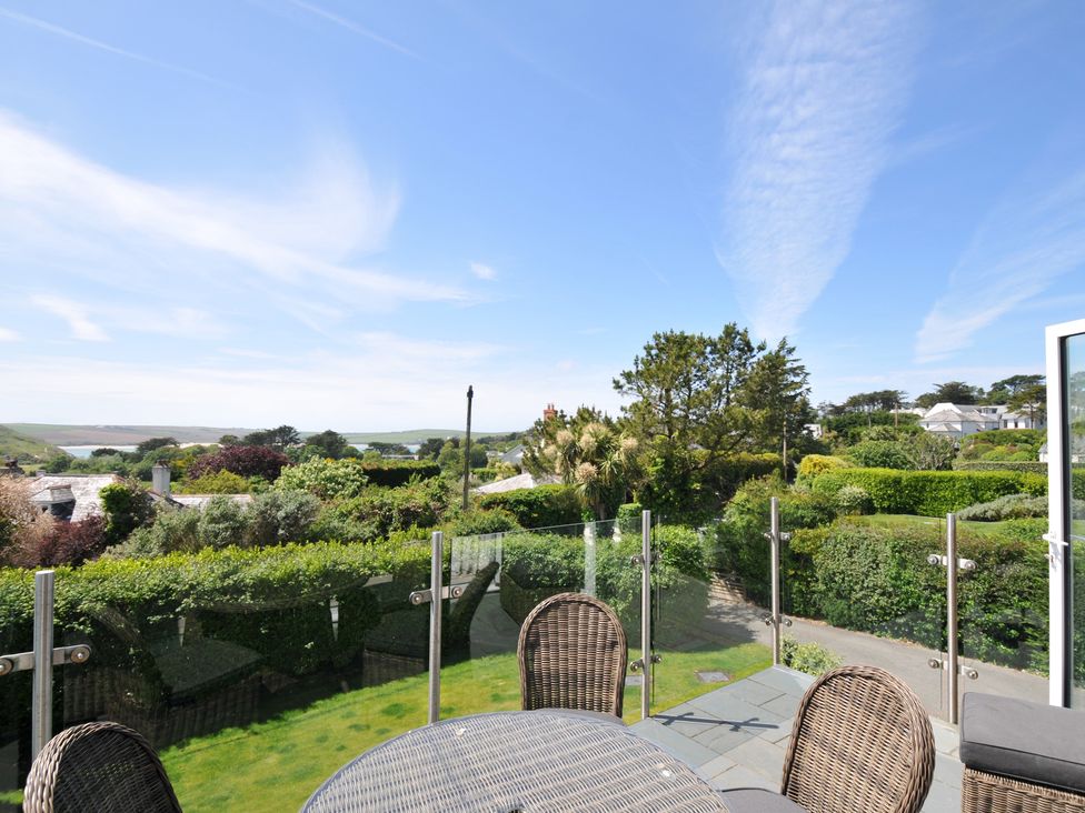 An outdoor area with a table and chairs overlooking greenery and houses at Farlands in Daymer Bay