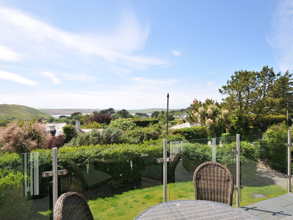 An outdoor area with a table and chairs overlooking a garden at Farlands Daymer Bay