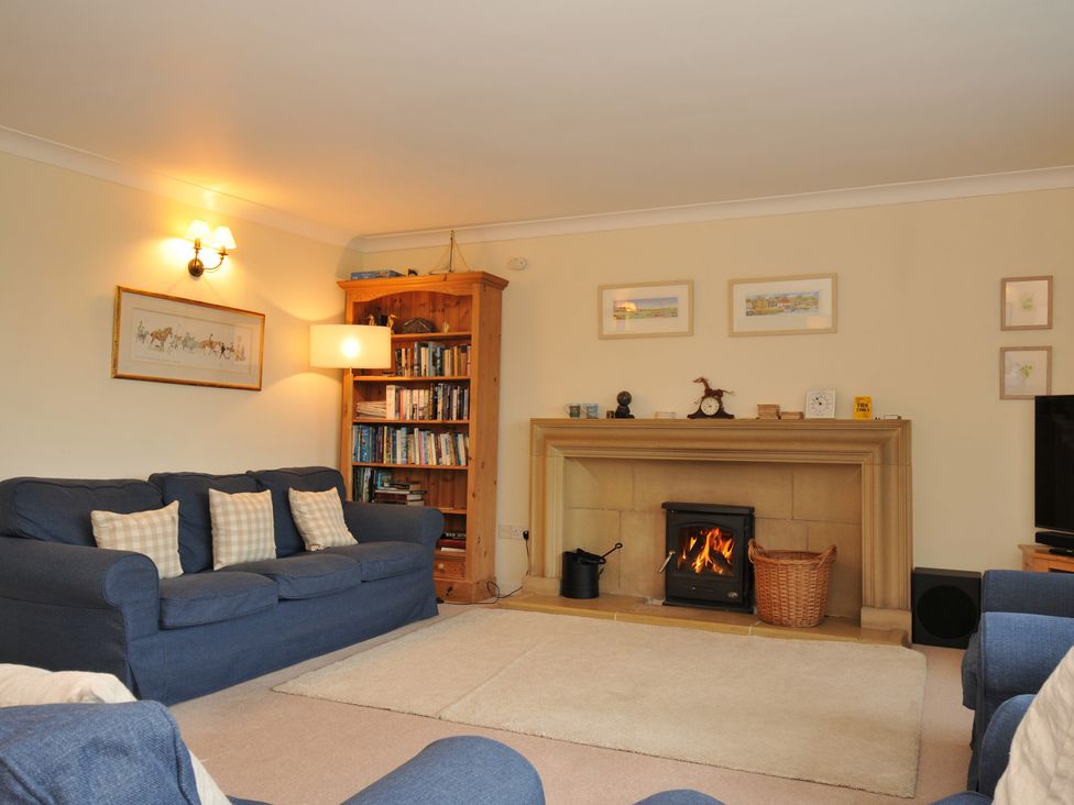 A living room with a fireplace and bookshelf at Tregillan in Rock