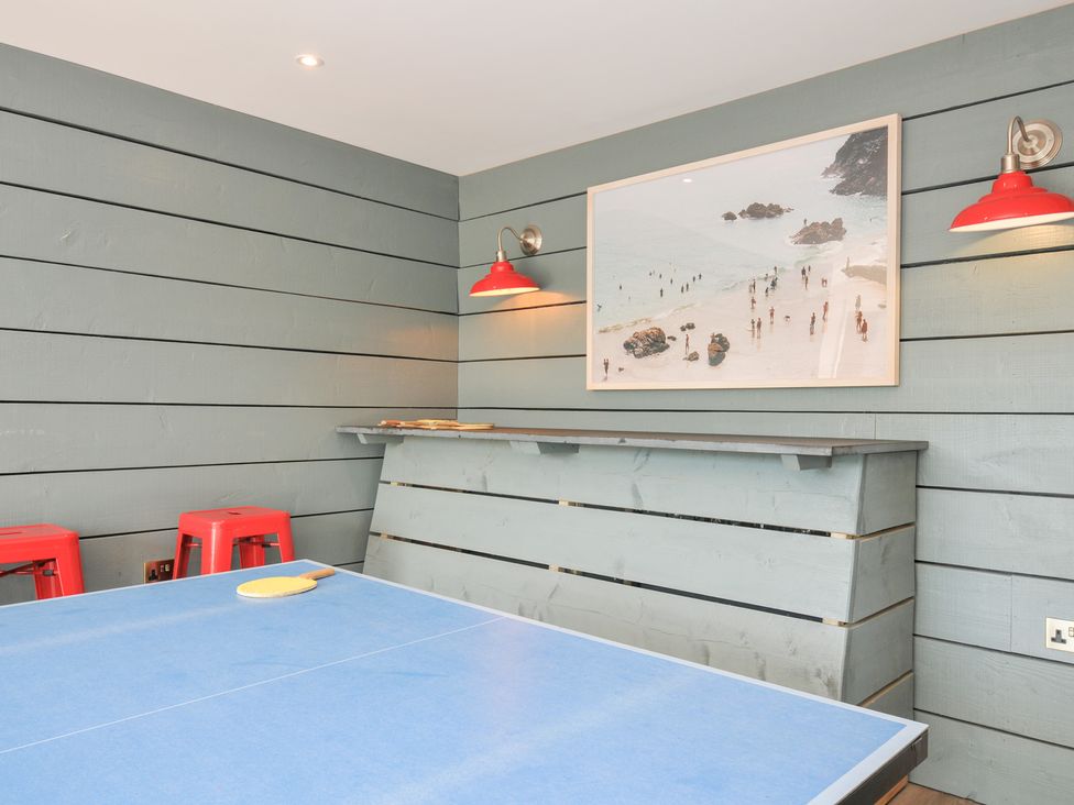 A game room with a table and red stools at Porthilly Brook in Rock