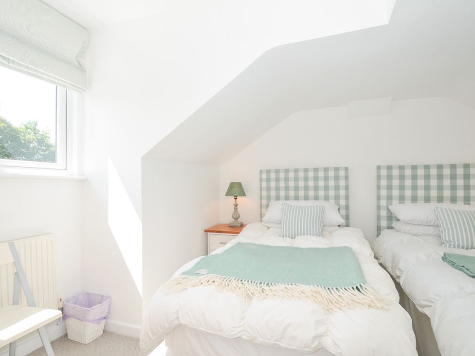 A bedroom with two beds and a lamp on a nightstand at Porthilly Brook in Rock