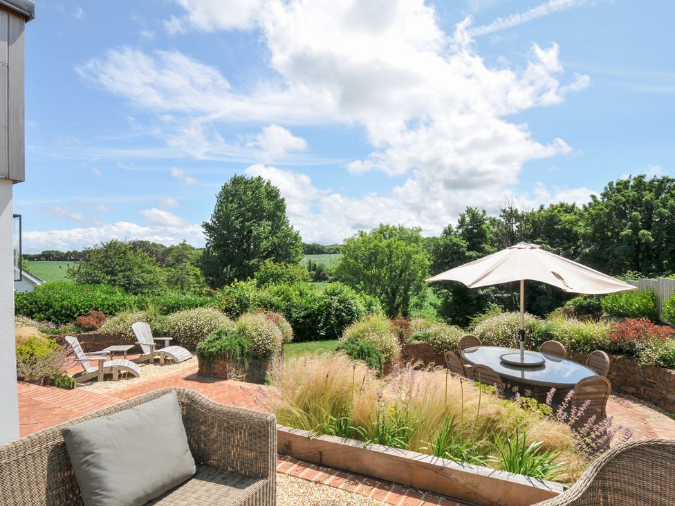 A garden with a table and chairs under an umbrella at Porthilly Brook in Rock