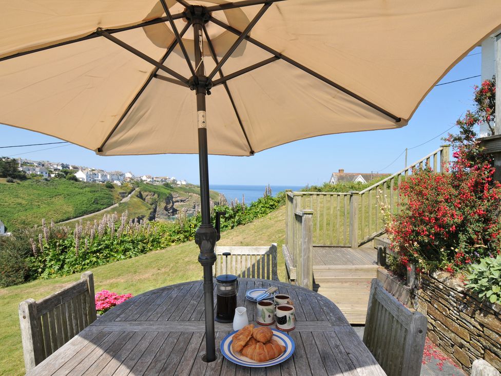 A table with cups and croissants under an umbrella at Cartway Cove, Port Isaac