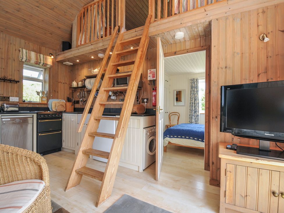 A living room with kitchen, staircase, and bed at Cartway Cabin, Port Isaac