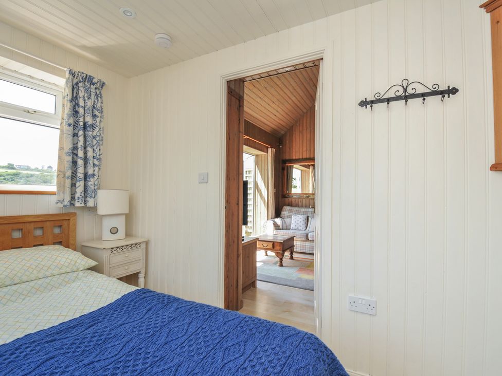 A bedroom with a bed and a doorway to another room at Cartway Cabin, Port Isaac
