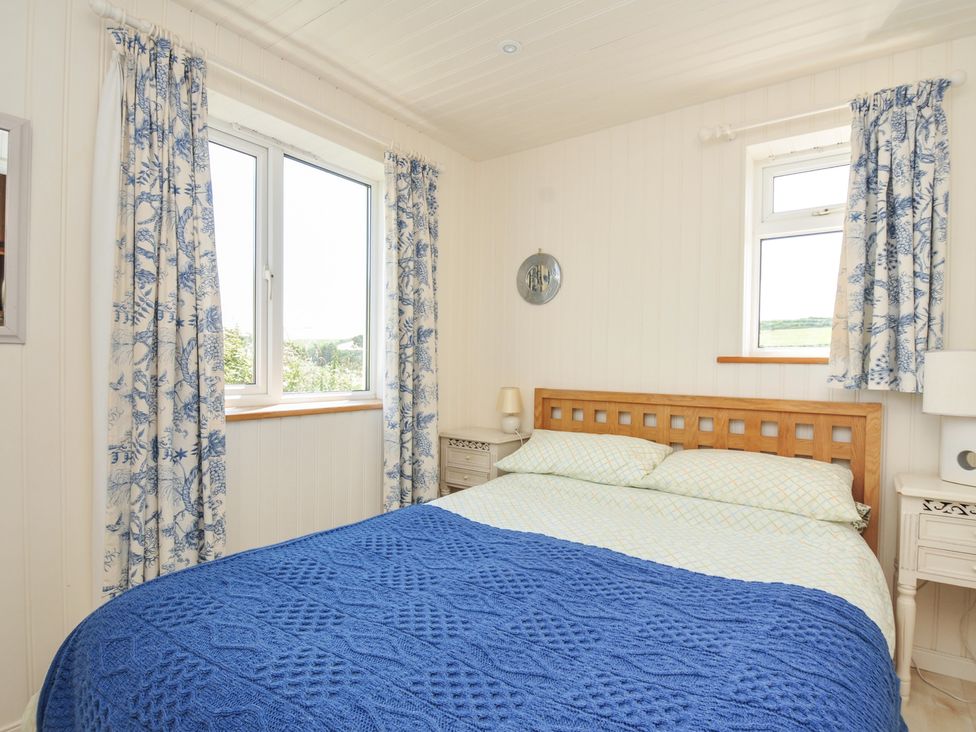 A bedroom with a bed and curtains at Cartway Cabin in Port Isaac
