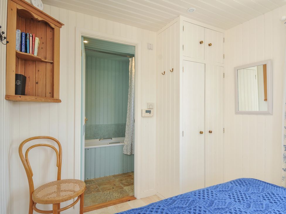 A bedroom with a closet, chair, and mirror at Cartway Cabin Port Isaac