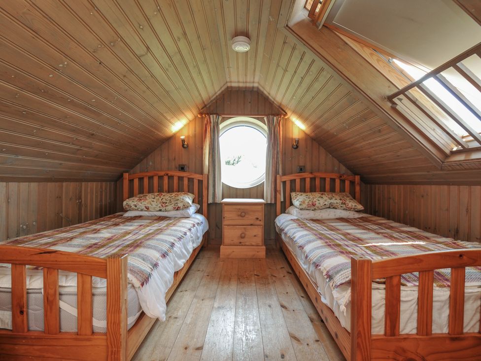 A bedroom with two beds and a wooden bedside table at Cartway Cabin Port Isaac