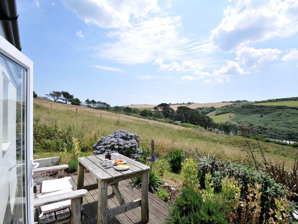 An outdoor setting with a table and chairs overlooking the landscape at Cartway Cabin in Port Isaac