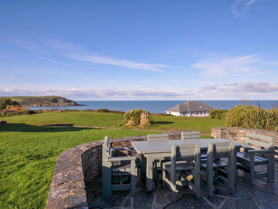 A garden with a table and chairs overlooking the ocean at Upper Gren in Trebetherick