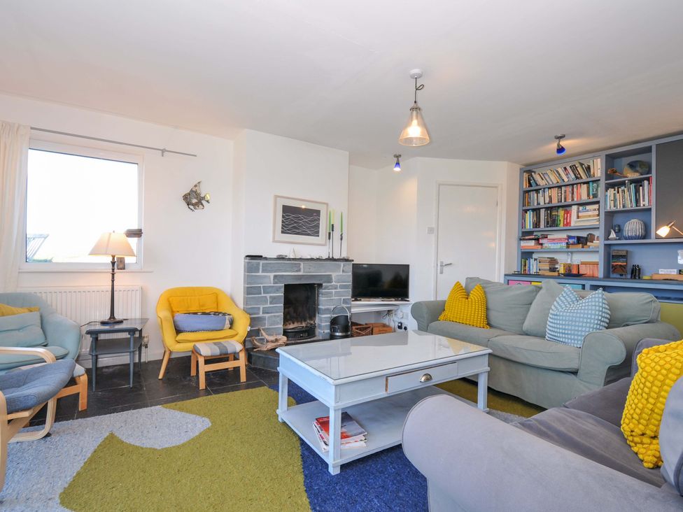 A living room with a fireplace and bookshelf at Upper Gren in Trebetherick